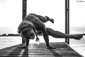 Wendy on a pier doing a hand stand with her body parallel to the pier.