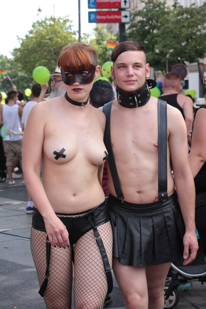 A young couple at some outdoor function with the girl topless except for tape covering her nipples.