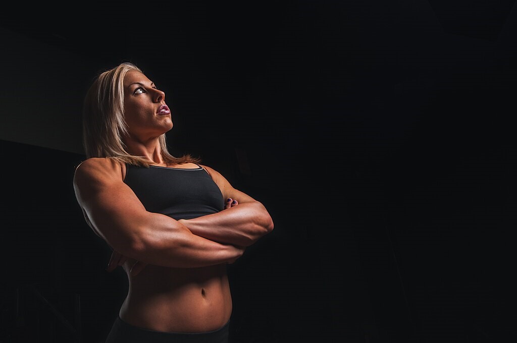 Muscular girl with her arms crossed looking upwards.