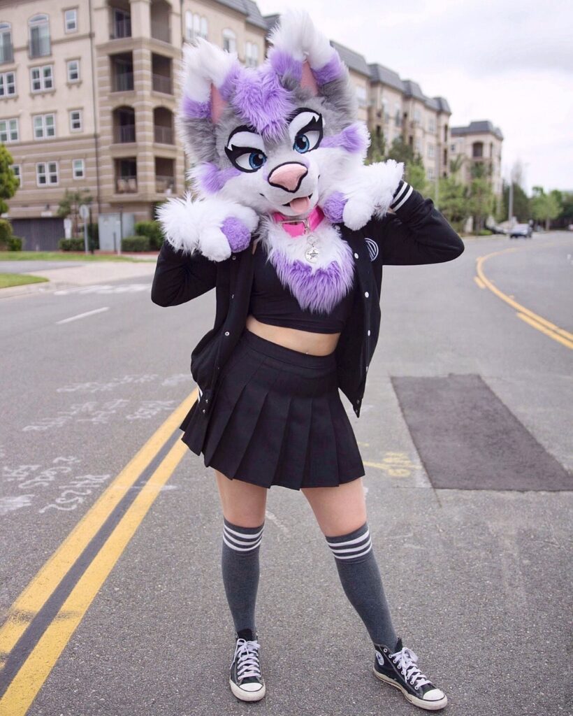 A girl standing in the street with a cute wolve head on.