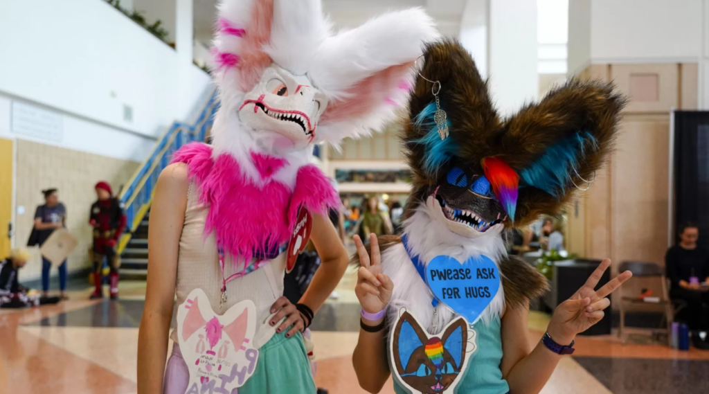 Two girls standing in an indoor public place with furry heads on.